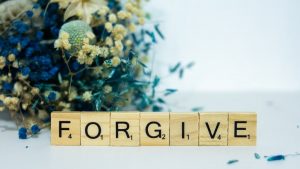 a wooden block that says for give next to a bouquet of flowers